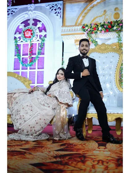 A regal portrait of the couple on their reception stage. The bride's elegant white and silver gown and soft makeup make her look like modern royalty.