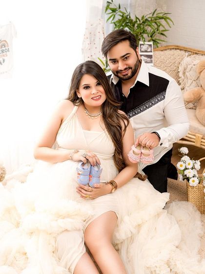 A fun gender reveal shot within a maternity session. The couple holds up both pink and blue booties, building anticipation for their big news.