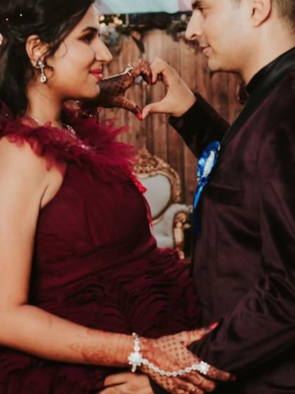 A sweet moment making a heart shape over the baby bump. This close-up shows the delicate texture of our ruffled maroon gown.