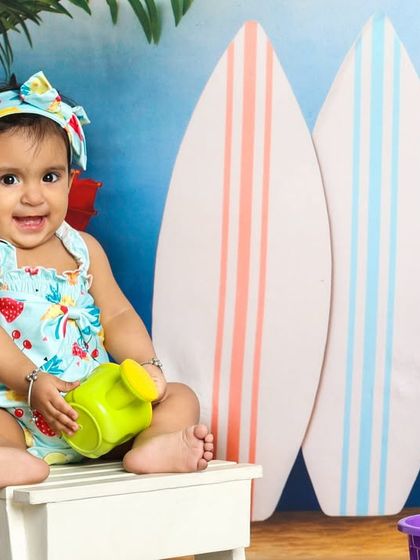 Sitting on her little beach chair, this baby is the picture of summer relaxation. The surfboard props add to the fun, beachy atmosphere.