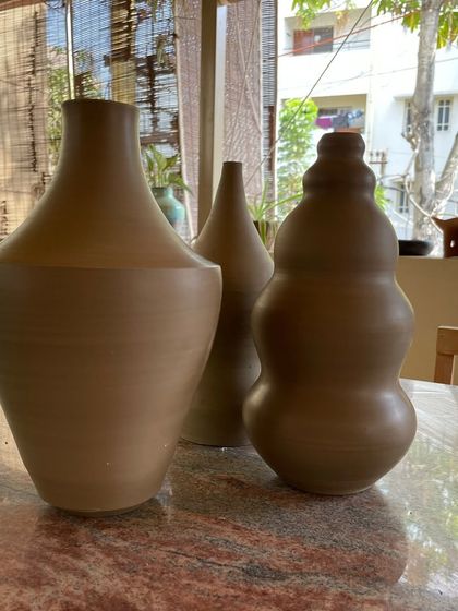 A collection of large, unglazed vases in various shapes and sizes. Each one is thrown on the wheel and showcases a different form, from classic curves to textured surfaces.