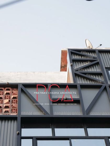 An upward view of the top portion of the Chadha Properties office facade, showing the structural frame, terracotta jaalis, and our firm's logo.