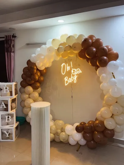 Our 'Teddy Bear Hug' theme is a crowd favorite for its cozy and neutral charm. This baby shower setup features a full ring balloon arch in brown, beige, and white, an 'Oh! Baby' neon sign, a classic cake plinth, and our popular transparent 'BABY' boxes.