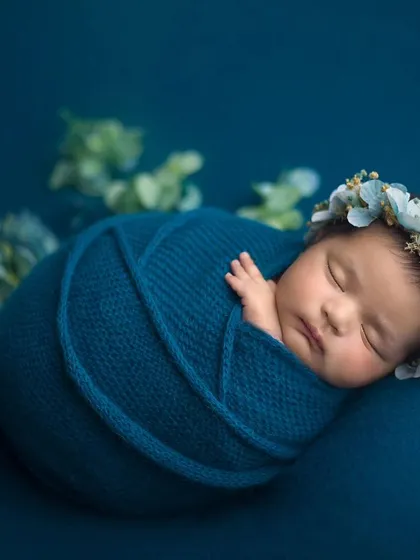 I specialize in the art of newborn swaddling, which keeps babies feeling secure, calm, and sleepy. This portrait showcases a classic wrap, complemented by a delicate floral crown for a touch of elegance.