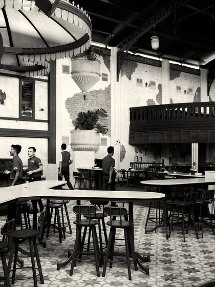 The bustling floor of the restaurant, showing the high-top tables and patterned tiles. The design accommodates both large groups and smaller parties.