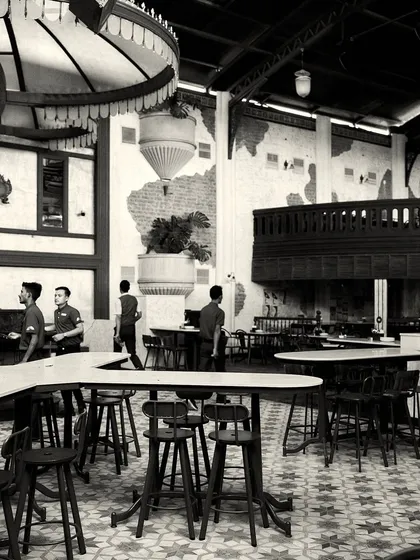 The bustling floor of the restaurant, showing the high-top tables and patterned tiles. The design accommodates both large groups and smaller parties.