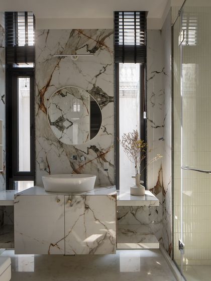 A marble sanctuary where veins of Indian marble flow seamlessly across surfaces. Tall windows reflect natural light, and a circular mirror amplifies the sense of space and openness.