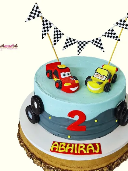 The full view of this 'Cars' themed cake for Abhiraj's second birthday. The handmade car toppers, checkered flags, and road design create a perfect racetrack for a little fan.