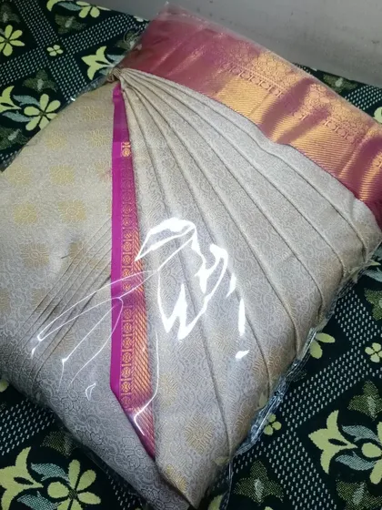 This off-white and pink saree is pleated, packed, and ready to give you a flawless drape.