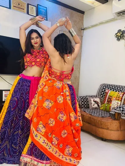 Two models in complementary patchwork Garba lehengas, one with an orange dupatta and one with a backless blouse.