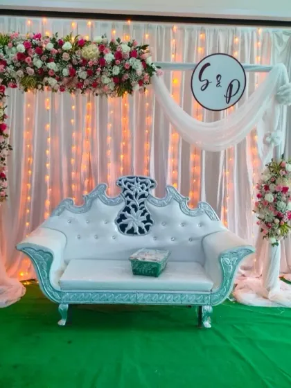 A bright, clear photo of the pink and white engagement stage in full light. This view clearly shows the custom monogram, the texture of the fairy light curtain, and the lush floral arch.