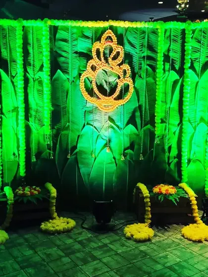 Inspired by nature, this unique backdrop uses a print of large banana leaves, giving it a very traditional South Indian feel. We accent it with marigold garlands and a central Ganesha motif made of flowers, lit with green uplighting for a dramatic effect.