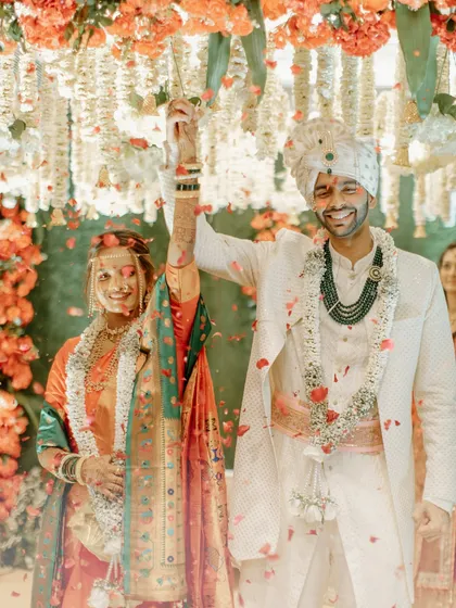 A joyful moment from a traditional Marathi wedding. The couple celebrates their union under a shower of petals, their happiness lighting up the frame.