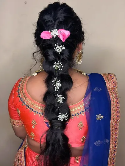 A view of the hairstyle from the back. The braided style is adorned with small flowers, adding a delicate touch to the look.