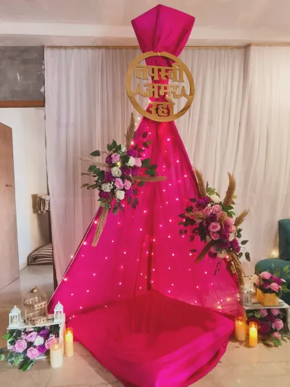A creative teepee-style seating arrangement for a Tapasvi ceremony. The bright pink fabric is decorated with flowers and fairy lights, creating a cozy and unique sacred space.