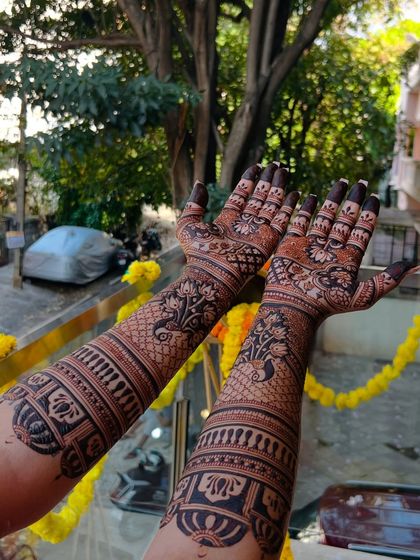 A view of the engagement mehendi stain in natural daylight, showing the rich color. The design includes traditional elements like paisleys and peacocks.