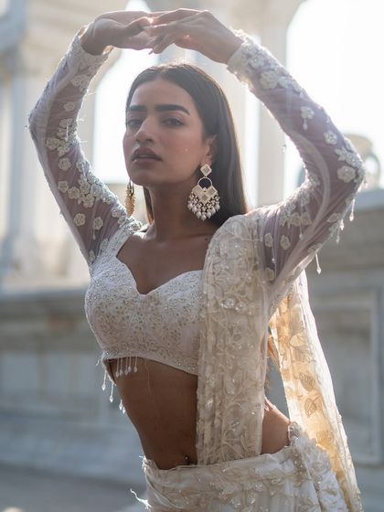 Drench yourself in pure elegance with this ivory lehenga featuring delicate threadwork and a full-sleeve blouse.