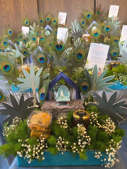 Themed gifting allows for such creative storytelling. This "Little Kanha" hamper, designed for a special welcome, features a miniature Krishna idol, peacock feathers, and sweet treats, all arranged in a beautiful, thematic display.