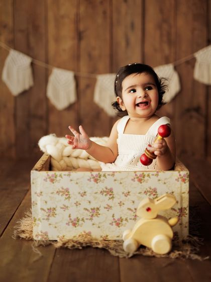 A pure, happy moment. This little girl is laughing while sitting in a floral box with her toys.