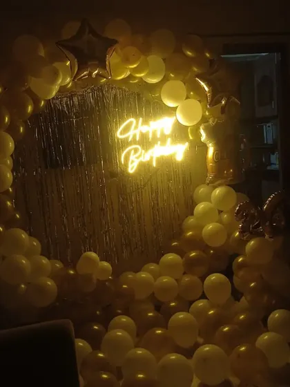 A duplicate image of the golden balloon ring with a neon sign, showing how it looks in a dark setting.