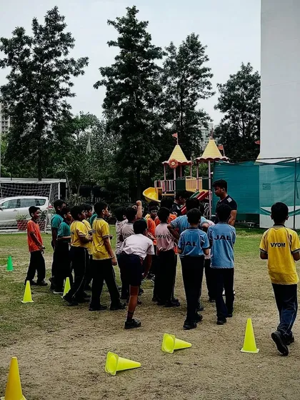 A group of kids gathered around a coach during a fun training exercise with cones at one of our community workshops.
