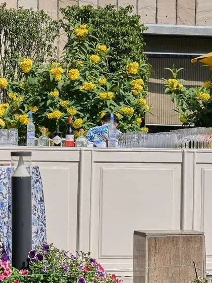 Another view of the garden bar, with a yellow umbrella providing shade for the cocktail tables.