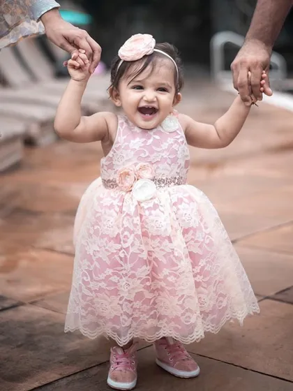 This is the smile that makes it all worthwhile. This little one is radiating pure joy in her custom pink lace dress, featuring delicate floral appliqués and a comfortable fit perfect for taking her first wobbly steps. It’s more than a dress; it’s a memory of pure happiness.