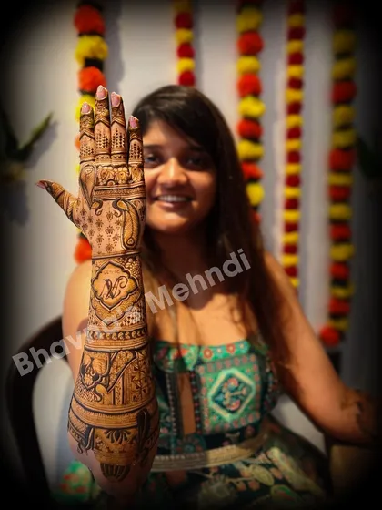 A happy client showing off her full back hand bridal mehndi. The design is rich with elephant motifs and personalized initials.