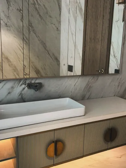 A close-up of a floating bathroom vanity featuring intricate CNC-cut patterns on the cabinet doors with a premium PU finish. This piece combines artistic texture with practical, moisture-resistant materials, complete with under-cabinet lighting for a hotel-like ambiance.