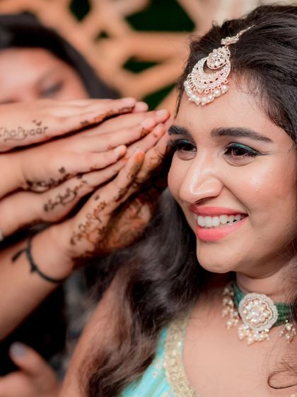 A happy, candid moment from a Mehendi ceremony. The makeup is fresh and glowing, with a pop of green on the waterline to add a playful touch.
