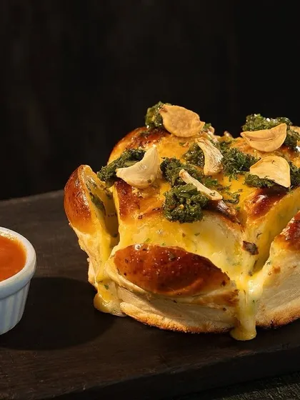 Meet my Cheesy Pull-Apart Bread. It's loaded with gooey cheese, crispy garlic, and fresh herbs, served with a side of rich marinara. It’s the perfect starter to get the party going.