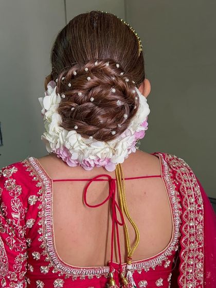 This twisted bridal bun is decorated with beautiful hydrangea flowers and small pearl details. The twists add texture and dimension, making it a unique and elegant choice.
