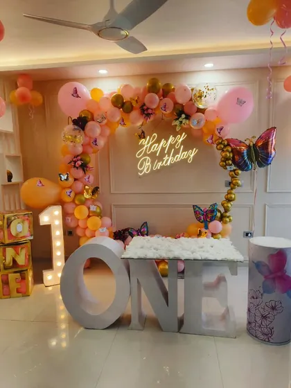 For this first birthday, I designed a magical butterfly theme. The setup includes a custom 'ONE' table for the cake, a shimmering balloon arch, and a personalized neon sign, all coming together to create a whimsical party space.