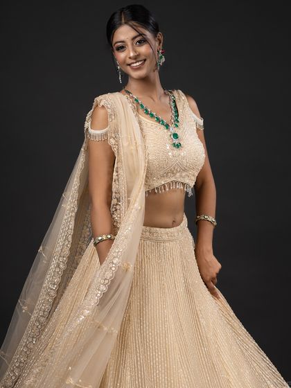 A full-length, smiling shot of the model in a cream lehenga, exuding joy and elegance.