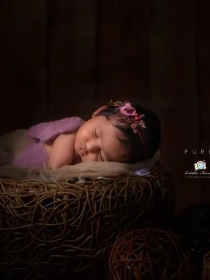 I love working with natural textures to create a warm, rustic feel. This little one is nestled in a woven basket with soft fabrics, set against a dark, wooden background to create a cozy, intimate portrait.