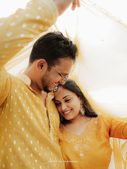 A sweet and intimate moment shared under a flowing yellow dupatta during their romantic beach pre-wedding session.