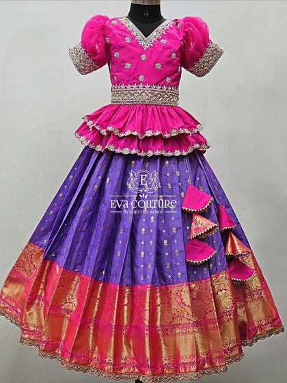 A beautiful combination of pink and purple. This Pattu Pavadai has a tiered peplum blouse and a scalloped border on the skirt.