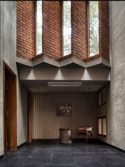 The foyer of the Brick House is a masterclass in materiality, combining fluted concrete, exposed brick, and dark stone to create a space that is both raw and refined.