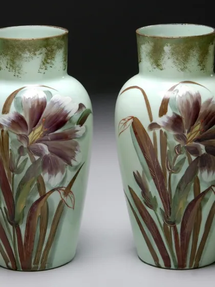 A beautiful pair of hand-painted baluster-shaped vases from the late Victorian period. Made of soft mint green Opaline glass, they feature delicate iris flowers, showcasing the fine craftsmanship of 19th-century European decorative arts. These pieces came to us from the distinguished collection of Meena Appachu.