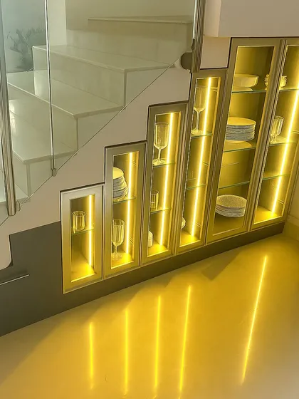 Our expertise lies in creating smart storage in unexpected places. Here, we transformed the underutilized area beneath a staircase into an elegant, backlit crockery unit with glass and aluminum-profile doors, turning storage into a design feature.