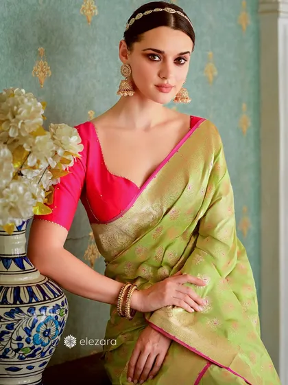 A model exudes elegance in a lime green saree with a bright pink blouse. The classic composition, with a decorative vase, is perfect for showcasing high-end ethnic wear.
