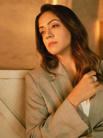 This close-up focuses on the delicate silver rings and the soft texture of the suit fabric.