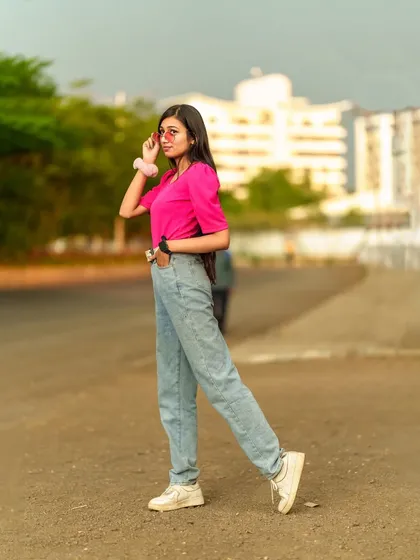 A classic street style pose, with the model looking over her shoulder, her pink top adding a vibrant pop of color to the urban scene.
