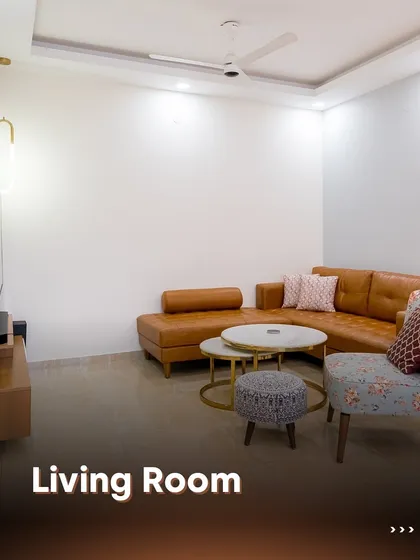 We designed this living room with a mix of comfort and style, featuring a tan leather sofa, a patterned accent chair, and a minimalist TV unit. The result is a warm and welcoming space perfect for relaxation.
