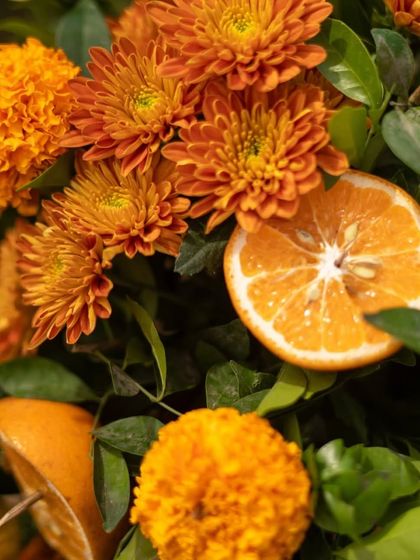 A creative floral detail using a slice of orange alongside marigolds. This small touch adds a fresh and unique element to the overall decor theme.
