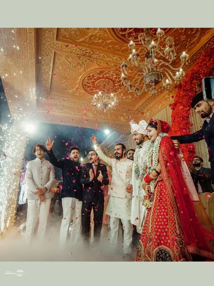 A celebration of love and friendship. The couple's friends shower them with petals and cheer them on during the Varmala ceremony, creating a moment of pure joy and energy.