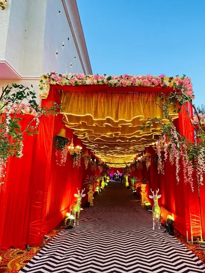The full view of the red and gold entrance, showing how the floral arrangements and draping create a grand and welcoming entryway.