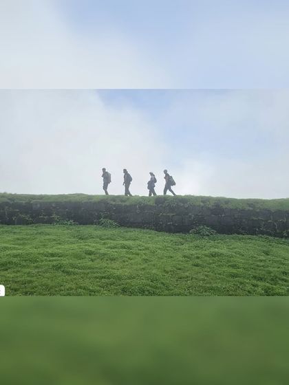 A silhouette of four trekkers walking along the wall of Korigad Fort during my Maharashtra trip. Fort treks offer a unique blend of history and natural beauty.