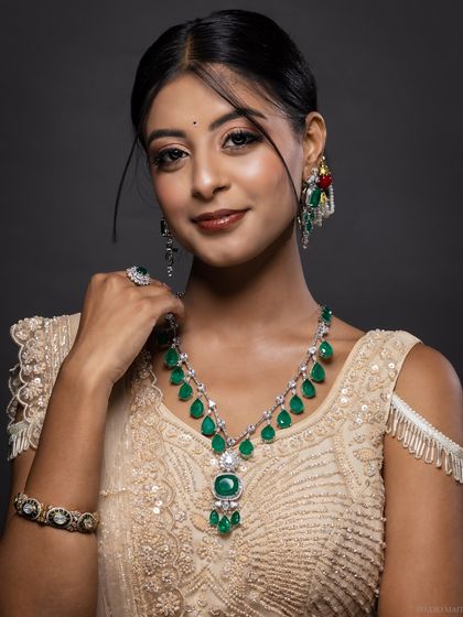 A model adorned with a complete emerald and diamond bridal jewellery set, including a necklace, earrings, and bangles. This is a perfect shot for a luxury bridal jewellery catalogue.