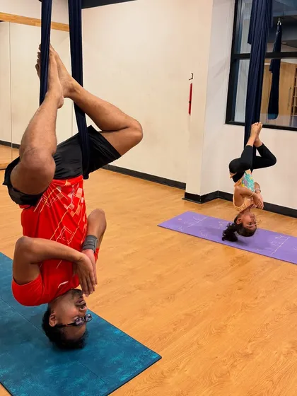 Father and daughter sharing a special moment during our family aerial yoga class. It's a wonderful way for families to bond, build trust, and have fun while hanging upside down together.